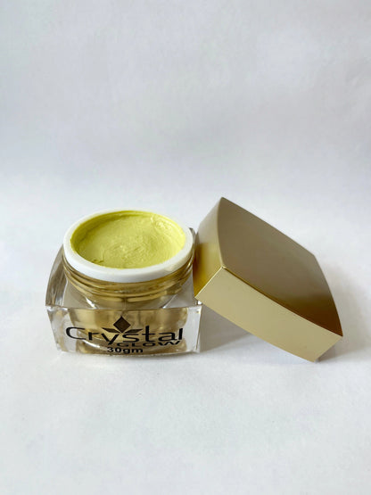 Jar of yellow cream with a white lid on a white background
